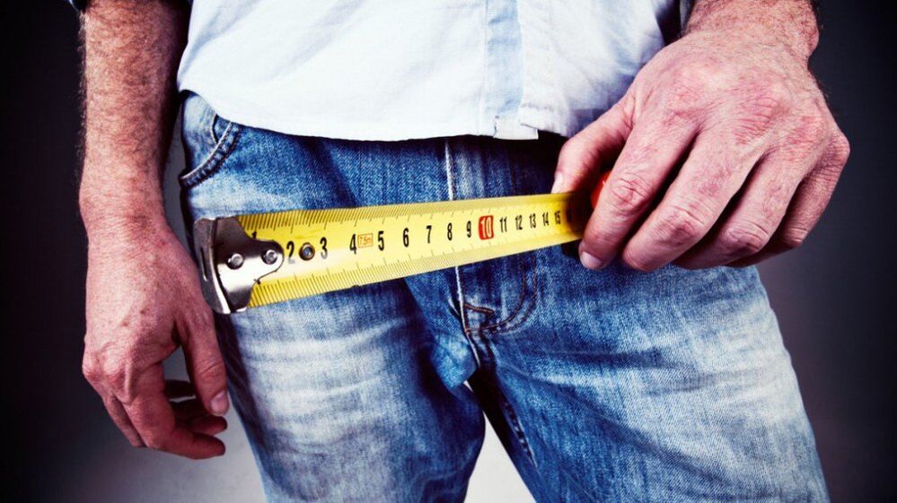man measures penis after enlargement with gel